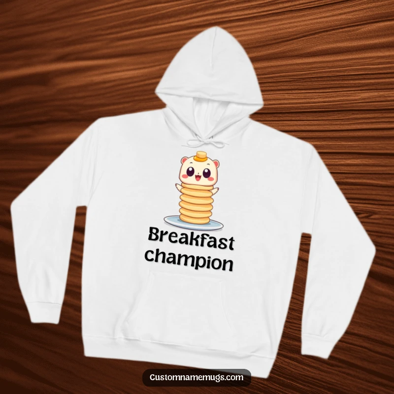 Funny hoodie showcasing a small, googly-eyed creature balancing a teetering stack of pancakes, perfect for cozy breakfast moments.